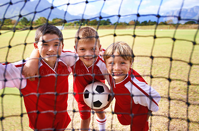 Buy stock photo Boys, soccer player and ball on goal net, smile and happy for game, field and child. Outdoor, playful and sport for childhood, portrait and athlete for match, alone and outside on football pitch