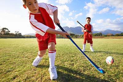 Buy stock photo Children, ball and playing hockey on green grass for game, sports or outdoor match together. Team, kids or players enjoying day on field for fitness, activity or practice in nature with blue sky