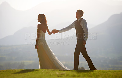 Buy stock photo Couple holding hands, bride and groom at wedding, outdoor in nature for social event with love and commitment. Man, woman and marriage, celebrate with trust and care together on hill with sunshine