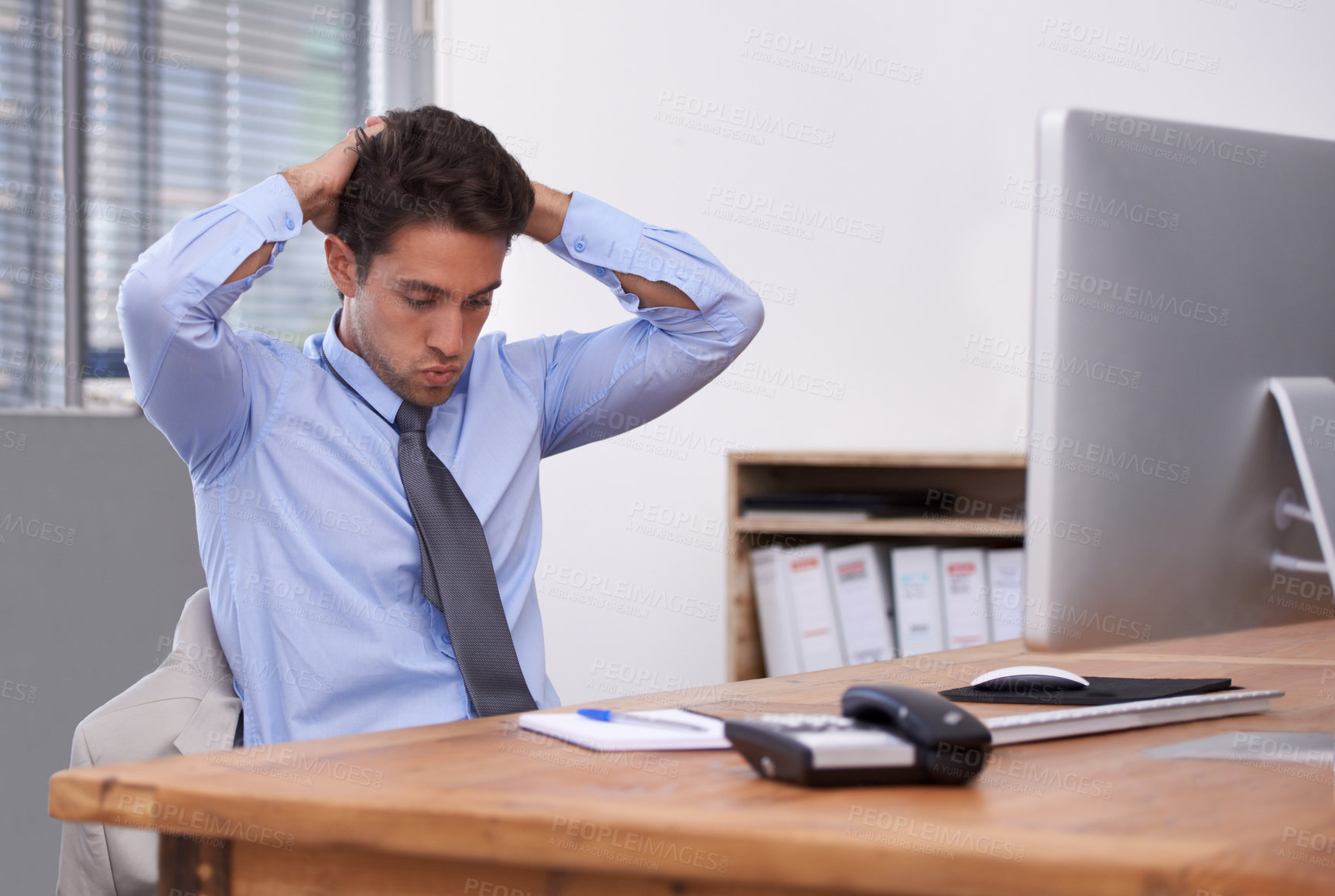 Buy stock photo A stressed out businessman sitting at his desk and looking frustrated