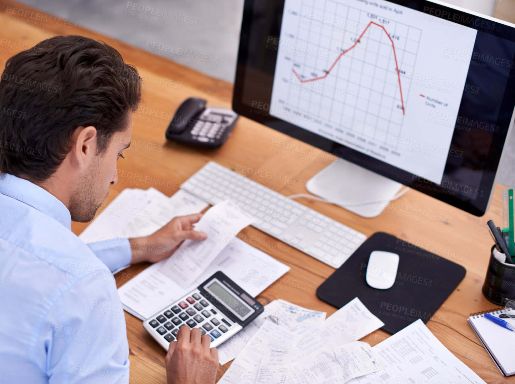 Buy stock photo Rearview shot of a handsome young businessman working at his desk