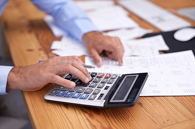 Buy stock photo Cropped shot of a businessman using a calculator in his office