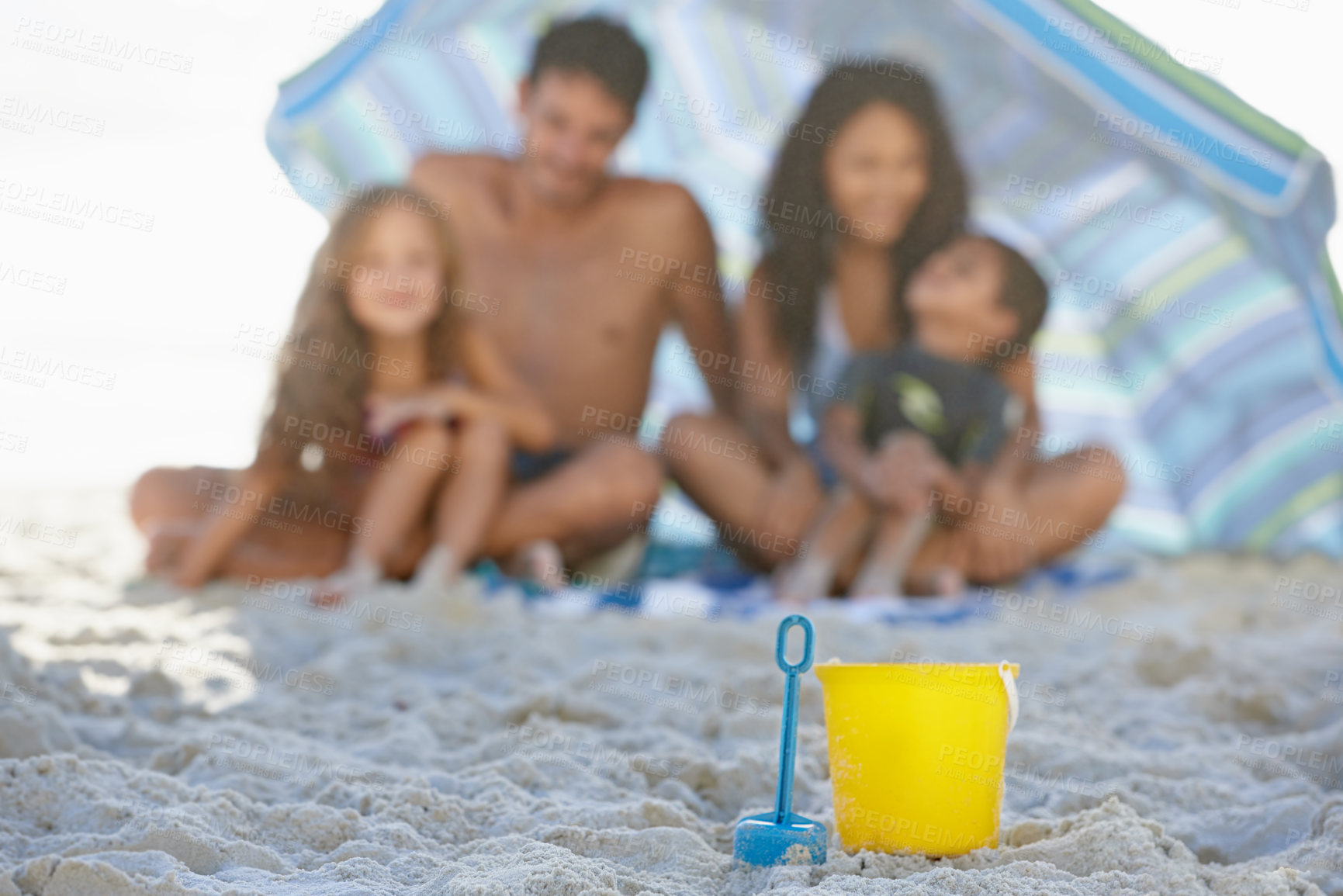Buy stock photo Big family, sand and box on beach with umbrella, spade or bucket for playing on ocean coast. Blue and yellow toys on sandy shore with people for fun bonding, relax or outdoor holiday weekend together