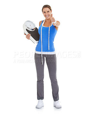 Buy stock photo Fit young woman giving you a thumb's up against a white background while holding a scale