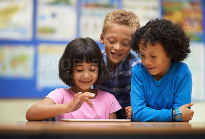 Buy stock photo Three school students working on a digital tablet in class