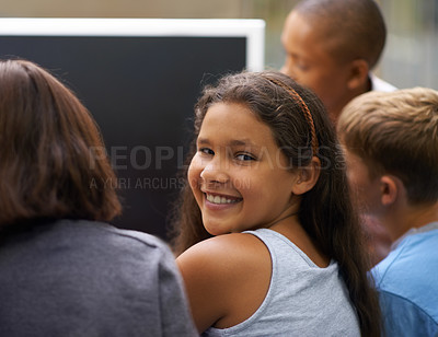 Buy stock photo Portrait of a young schoolgirl looking back while working on a computer with her friends