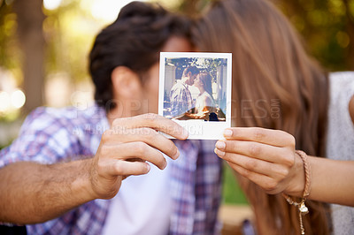 Buy stock photo Couple, photograph and valentines day date with love, kiss and affection in outdoor park for memory. Happy man and woman together on a picnic with polaroid paper picture in hands on holiday outdoor