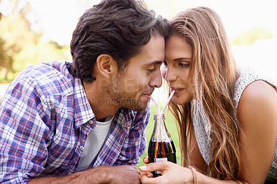Buy stock photo Young couple drinking soda together in park, summer holiday or valentines date for outdoor romance and love. Relax, happy people or woman with partner sharing a cola bottle and straw in garden picnic