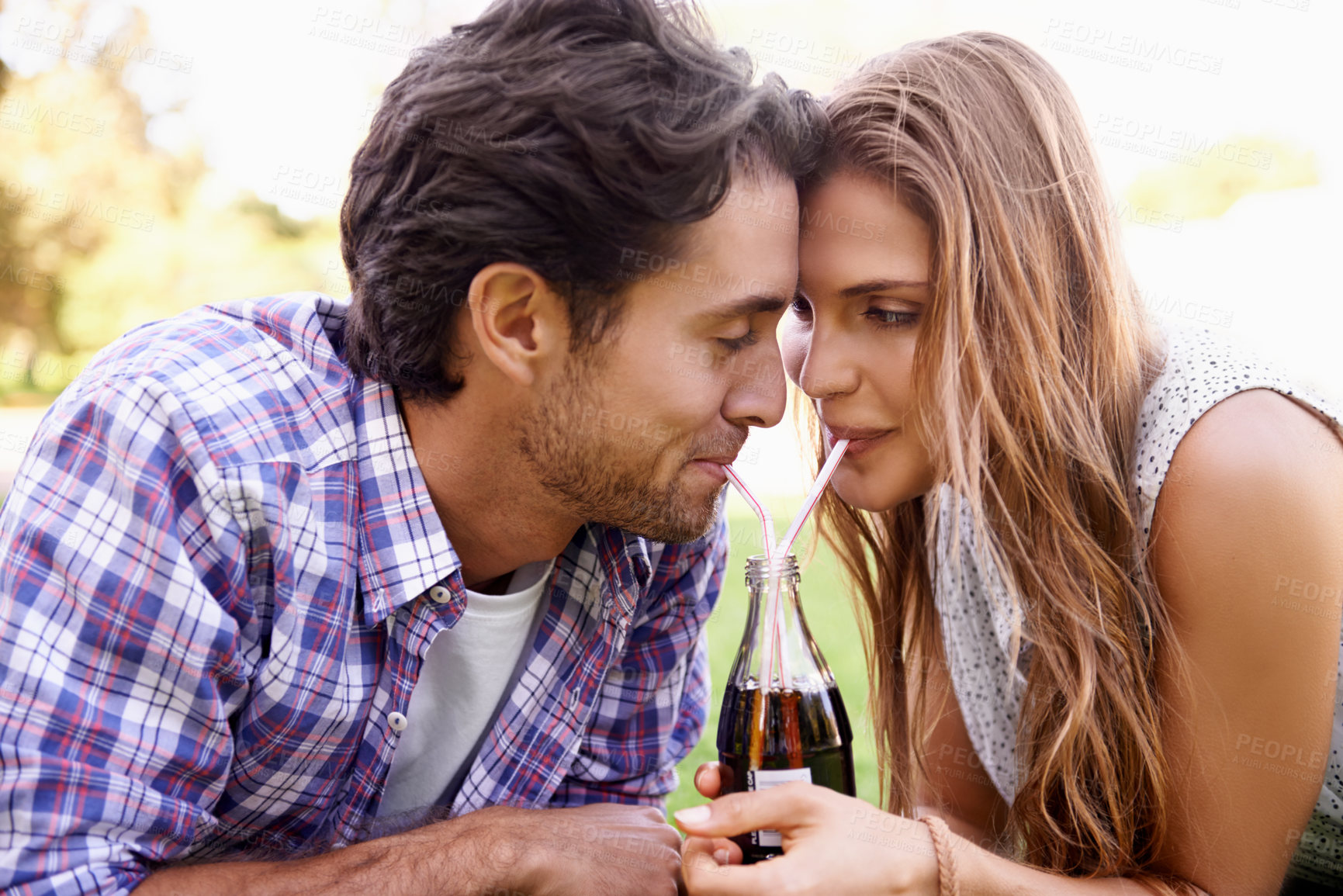 Buy stock photo Young couple drinking soda together in park, summer holiday or valentines date for outdoor romance and love. Relax, happy people or woman with partner sharing a cola bottle and straw in garden picnic