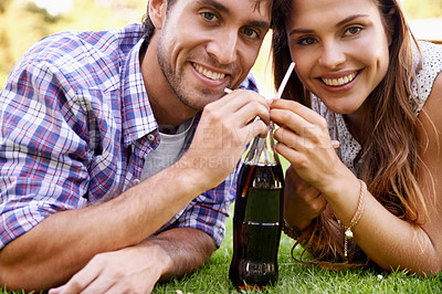 Buy stock photo Portrait, love and drink with a couple in the park, lying on the grass together for a romantic picnic. Face, drinking and dating with a man and woman bonding outdoor on grass during a summer date