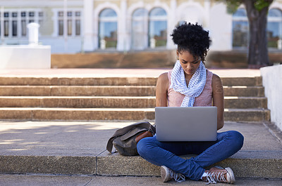 Buy stock photo An ethnic woman sitting on the steps of her college doing research on her laptop