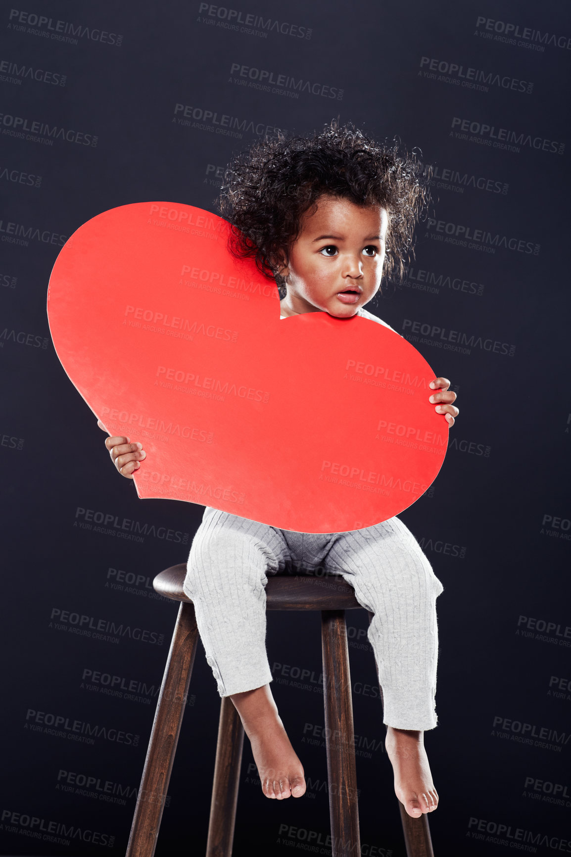 Buy stock photo Studio shot of a cute little girl holding a big heart isolated on black