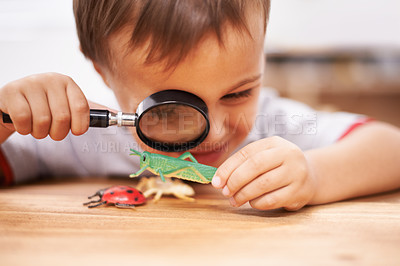 Buy stock photo Shot of a young boy inspecting his toys with a magnifying glass