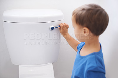 Buy stock photo Shot of a cute young boy flushing a toilet