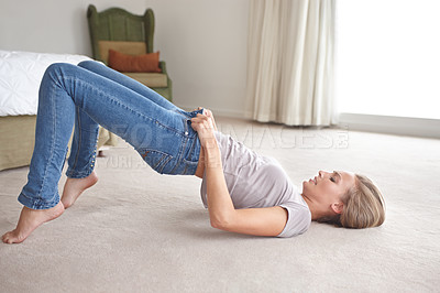 Buy stock photo A young woman struggling to pull on her jeans