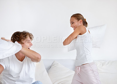 Buy stock photo A young couple wearing pajamas and having a pillow fight together