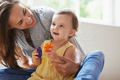 Buy stock photo Shot of a cute baby girl sitting on the floor with her mom and playing with toys