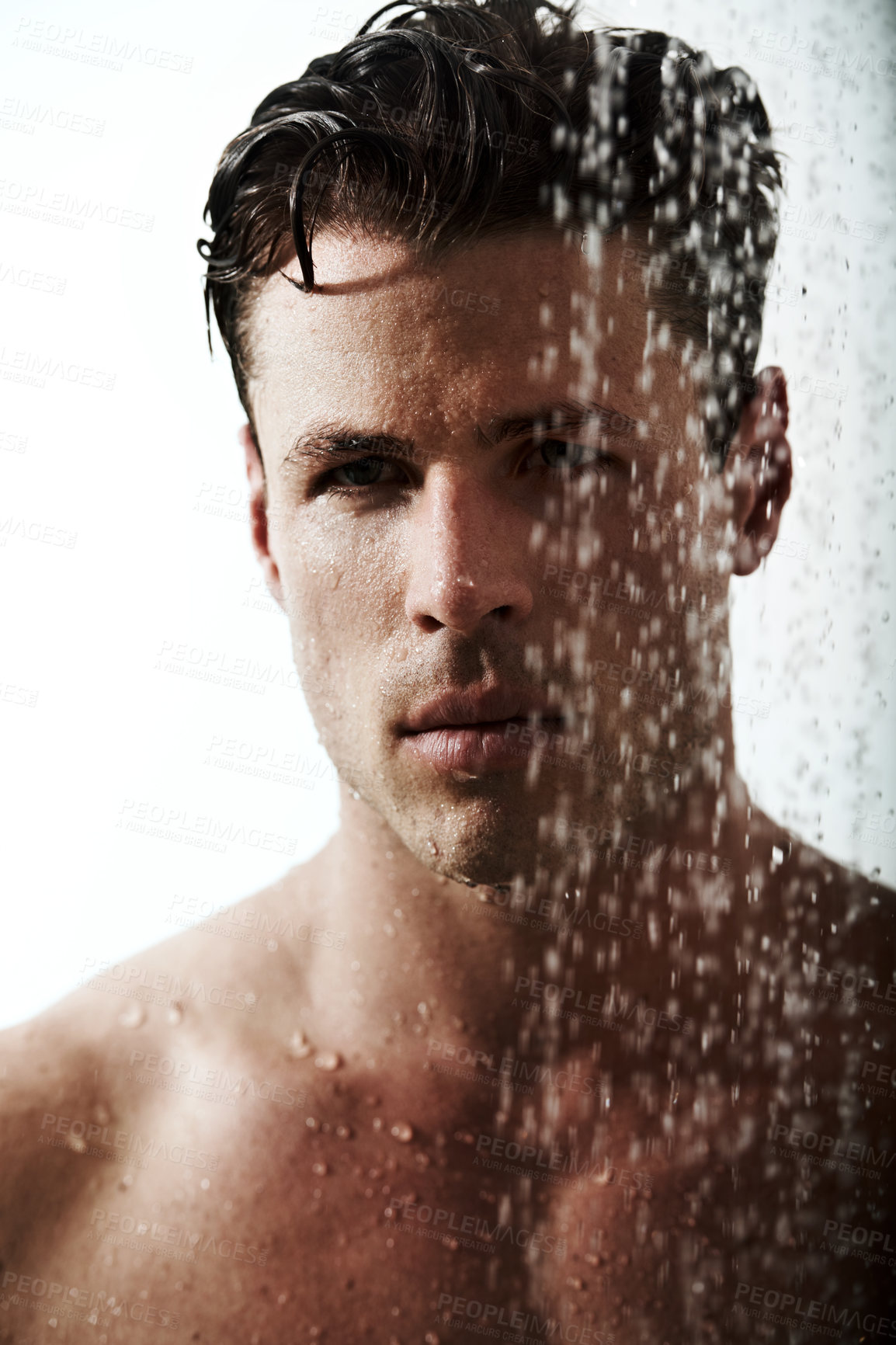 Buy stock photo Serious portrait of man in shower to relax, cleaning hair and body for morning wellness, hygiene and routine. Grooming, skincare and face of male model with muscle in water splash, self care and calm