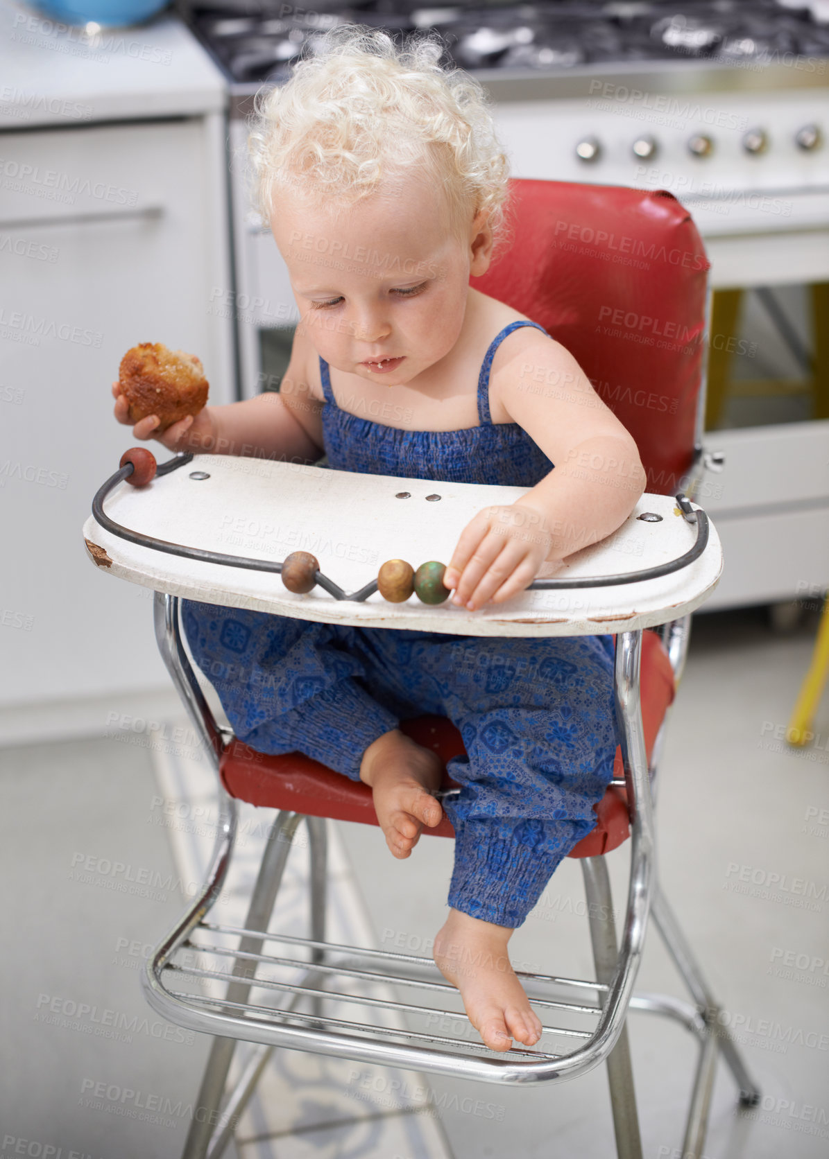 Buy stock photo Child, high chair and eating cupcake, food and breakfast sweets at home in kitchen. Young kid, hungry toddler and muffin dessert, sugar and pastry snack for cute adorable girl in house in the morning