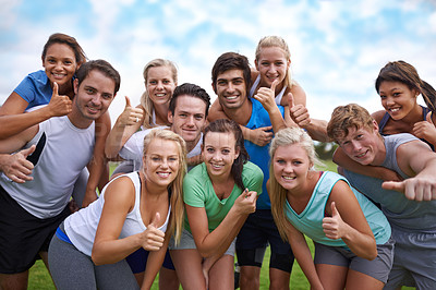 Buy stock photo A group of happy young people giving a thumb's up to the camera while standing on a sportsfield