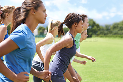 Buy stock photo A group of young women running on a sportsfield together