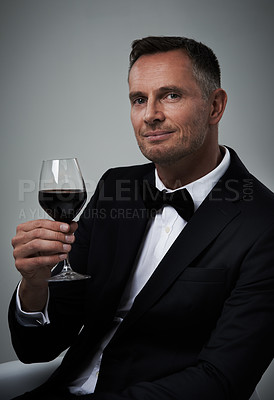 Buy stock photo Tuxedo, red wine and man portrait with alcohol in a suit feeling classy with a luxury drink. Gray background, isolated and studio with a model, agent or actor with a glass of rich person with mockup