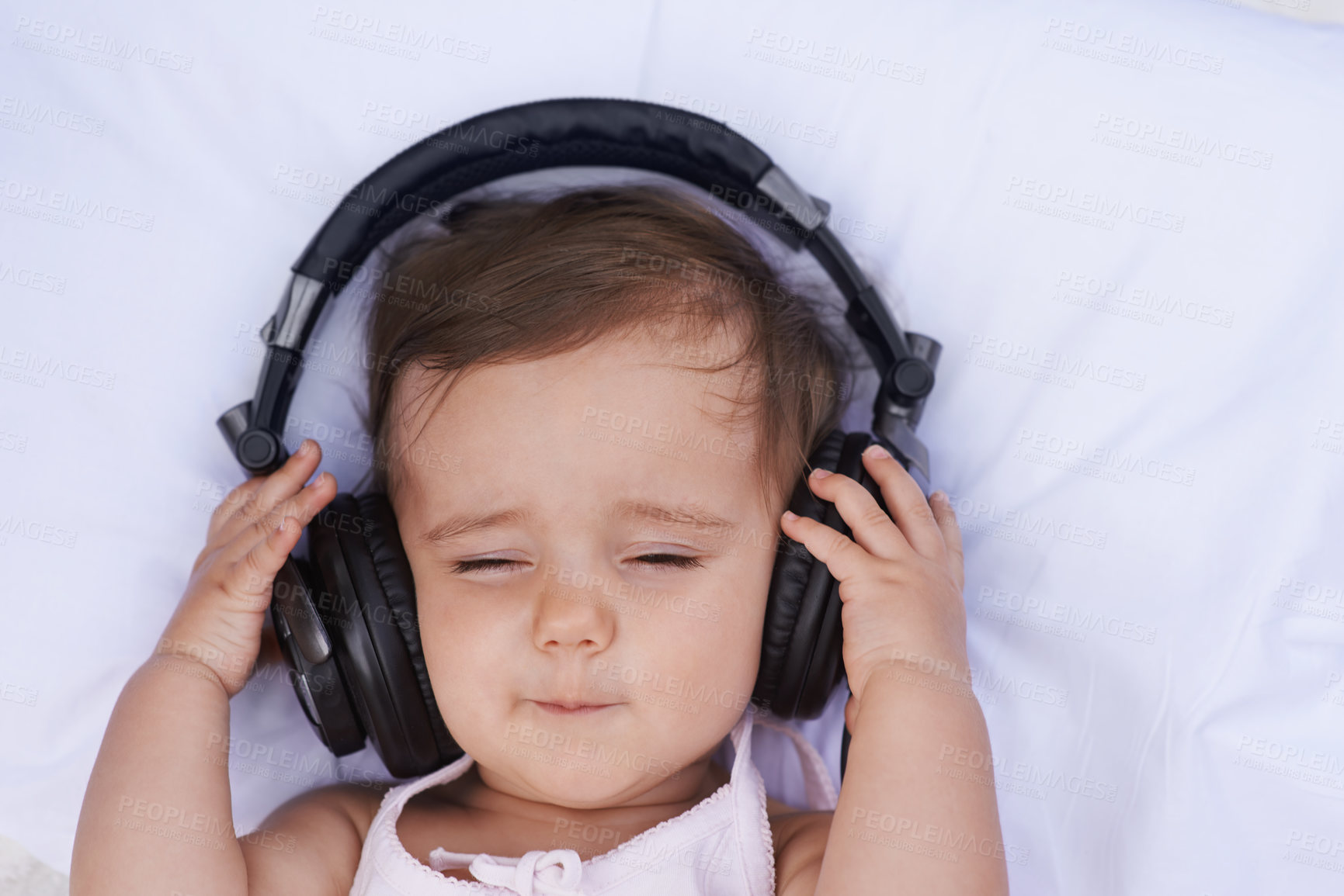 Buy stock photo A cute young baby girl listening to music on headphones