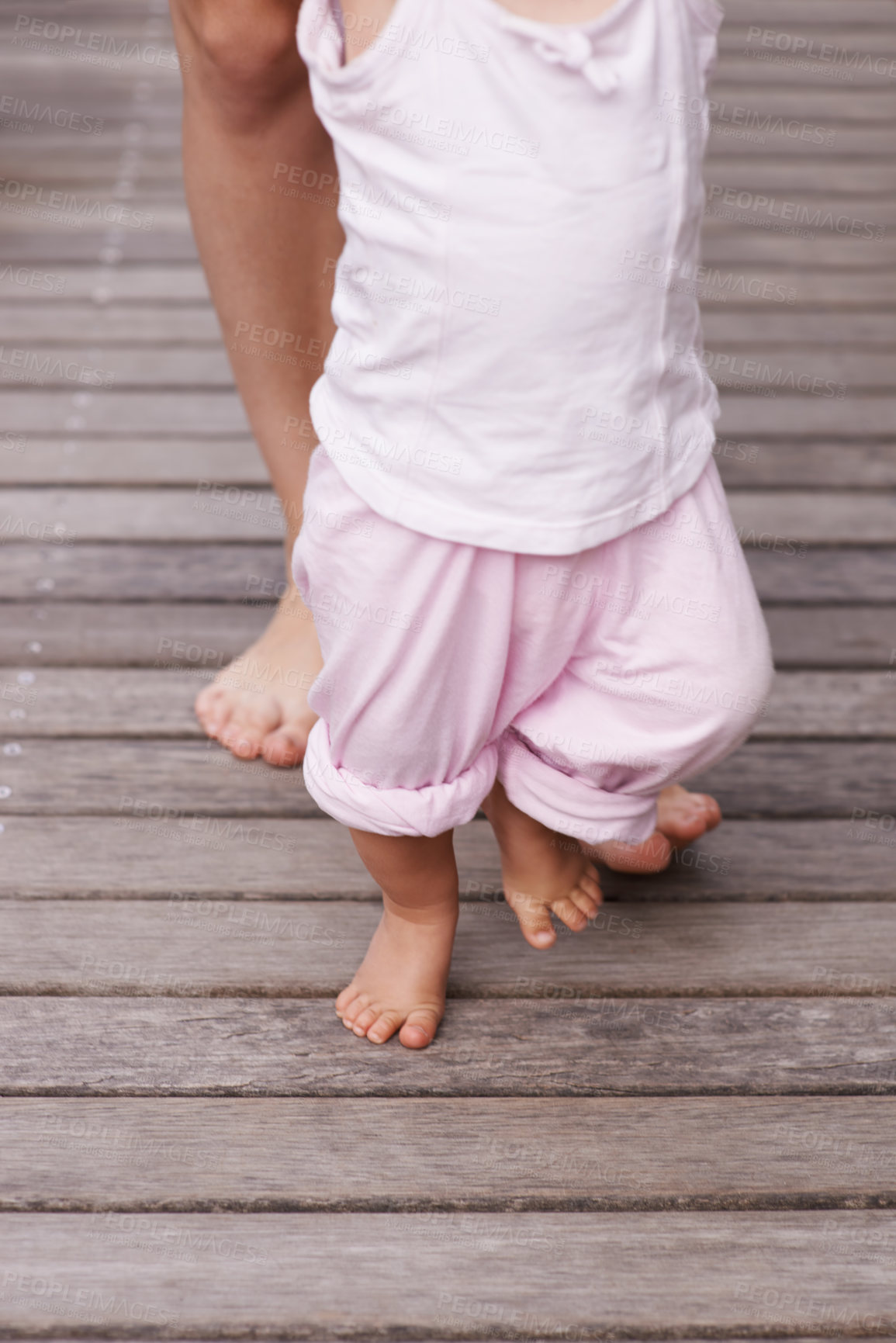 Buy stock photo Baby, feet and mom teaching with love, bonding and child care together and youth outdoor. Family, support and young kid with learning, holding and barefoot with trust, toddler and patio with mother