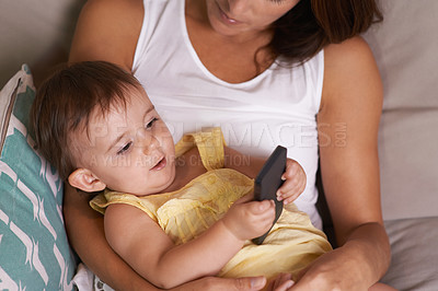 Buy stock photo Mother, baby and relaxing on smartphone in living room, playing games and curious for technology. Mom, toddler and happy girl or child and  internet connection on couch, mobile app and security
