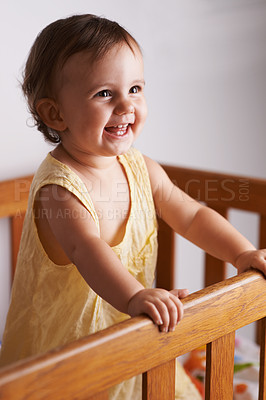 Buy stock photo Cute, laughing and a child in a crib for playing, wake up or comfort in a bedroom. Happy, baby and a young kid in a nursery or room for thinking, idea or innocent standing for development in a home