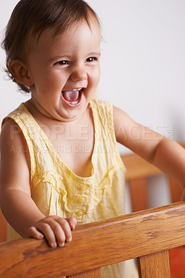 Buy stock photo Cute, happy and a child in a crib for playing, wake up or comfort in a bedroom. Laughing, baby and a young kid in a nursery or room for thinking, idea or innocent standing for development in a home