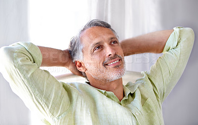 Buy stock photo A mature man relaxing at home with his hands behind his head