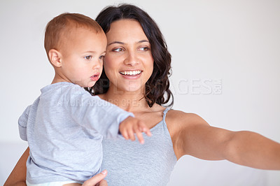 Buy stock photo Mom holding toddler with smile, pointing and child care with support at home in morning. Happy woman, baby boy and bonding together in bedroom with development, trust and safety with mothers love.