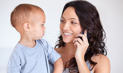 Buy stock photo Mom holding toddler in home with phone call, smile and child care with support in morning. Happy woman, baby boy and bonding together in bedroom with chat on cellphone, multitasking and mothers love.