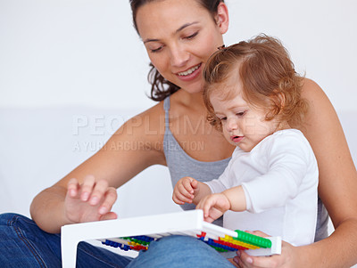 Buy stock photo A cute baby girl being taught by her mother how to use an abacus