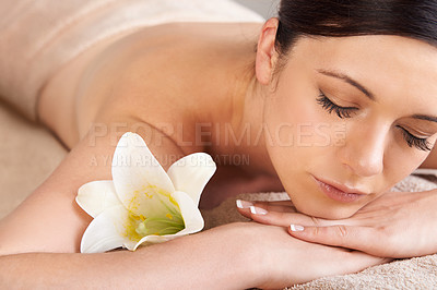 Buy stock photo Cropped view of a young woman relaxing at a spa with a fresh flower nearby