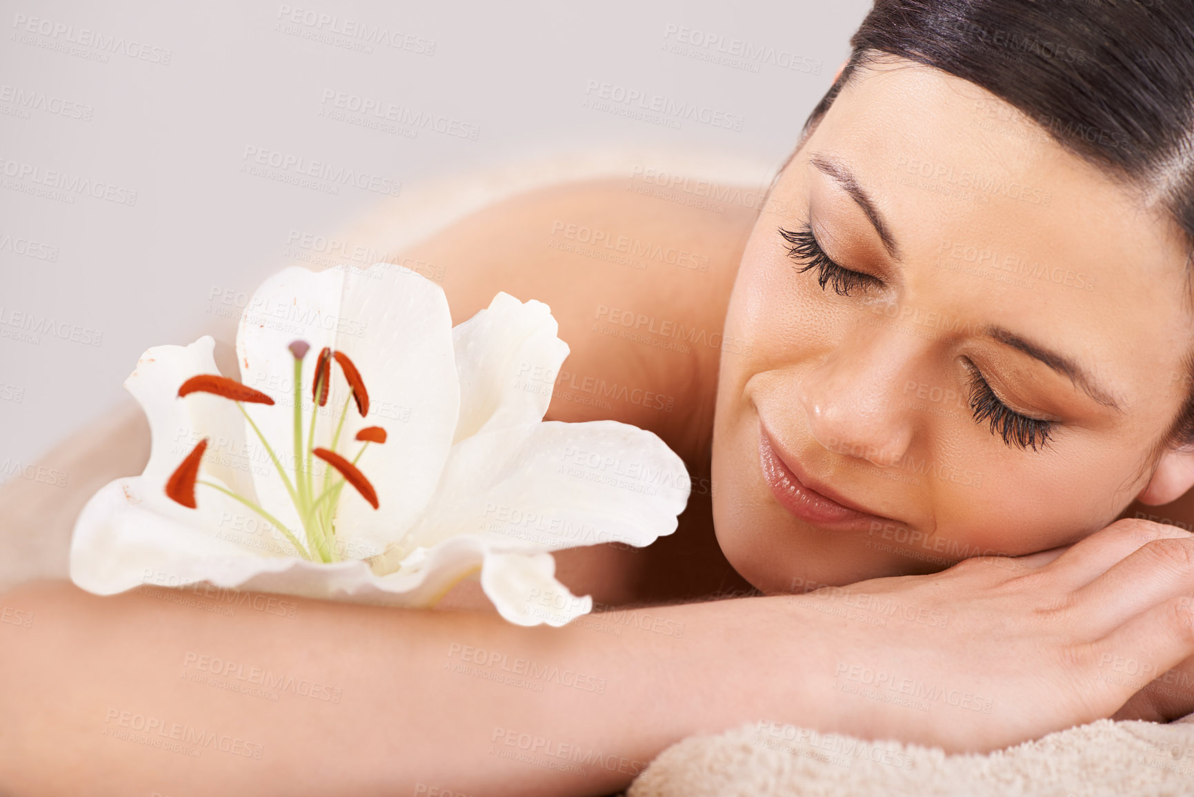 Buy stock photo Cropped view of a young woman relaxing at a spa with a fresh flower nearby