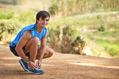 Buy stock photo A young teenager tying his shoe laces before going for a run in the forest