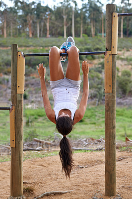 Buy stock photo A young woman hanging upside down by her legs and using her core to pull herself up