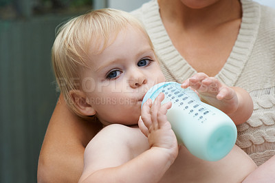 Buy stock photo A baby boy drinking milk from his bottle while being held by his mother