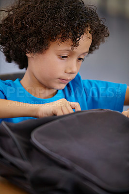 Buy stock photo Boy, education and school bag in a classroom, student and searching with learning, study and table. Kid, child development and happy with a backpack, desk and confident with information and relax