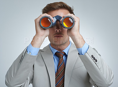Buy stock photo A young businessman looking through a pair of binoculars