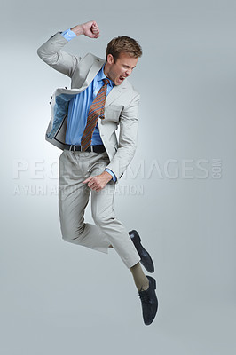 Buy stock photo Businessman, celebration and jumping for success in studio, winner and fist pump for triumph. Male person, professional and victory or accomplishment, cheering and energy or bonus by gray background