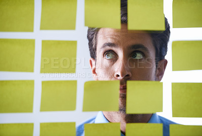 Buy stock photo Creative man, face and thinking in sticky note for schedule brainstorming or planning tasks on glass board at office. Male in doubt, decision or problem solving for startup idea strategy at workplace