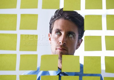 Buy stock photo Creative man, face and thinking for sticky note, brainstorming or planning tasks on glass board at office. Male person in problem solving, idea strategy or solution for startup decision at workplace