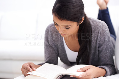 Buy stock photo Young woman, reading book on sofa and learning for home education, literature or language with leisure. Student or person relax in living room or lounge with novel or story for knowledge or studying