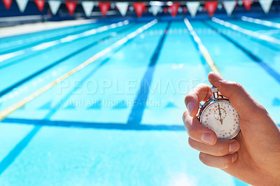 Buy stock photo Cropped shot a hand holding a stopwatch infront of a swimming pool