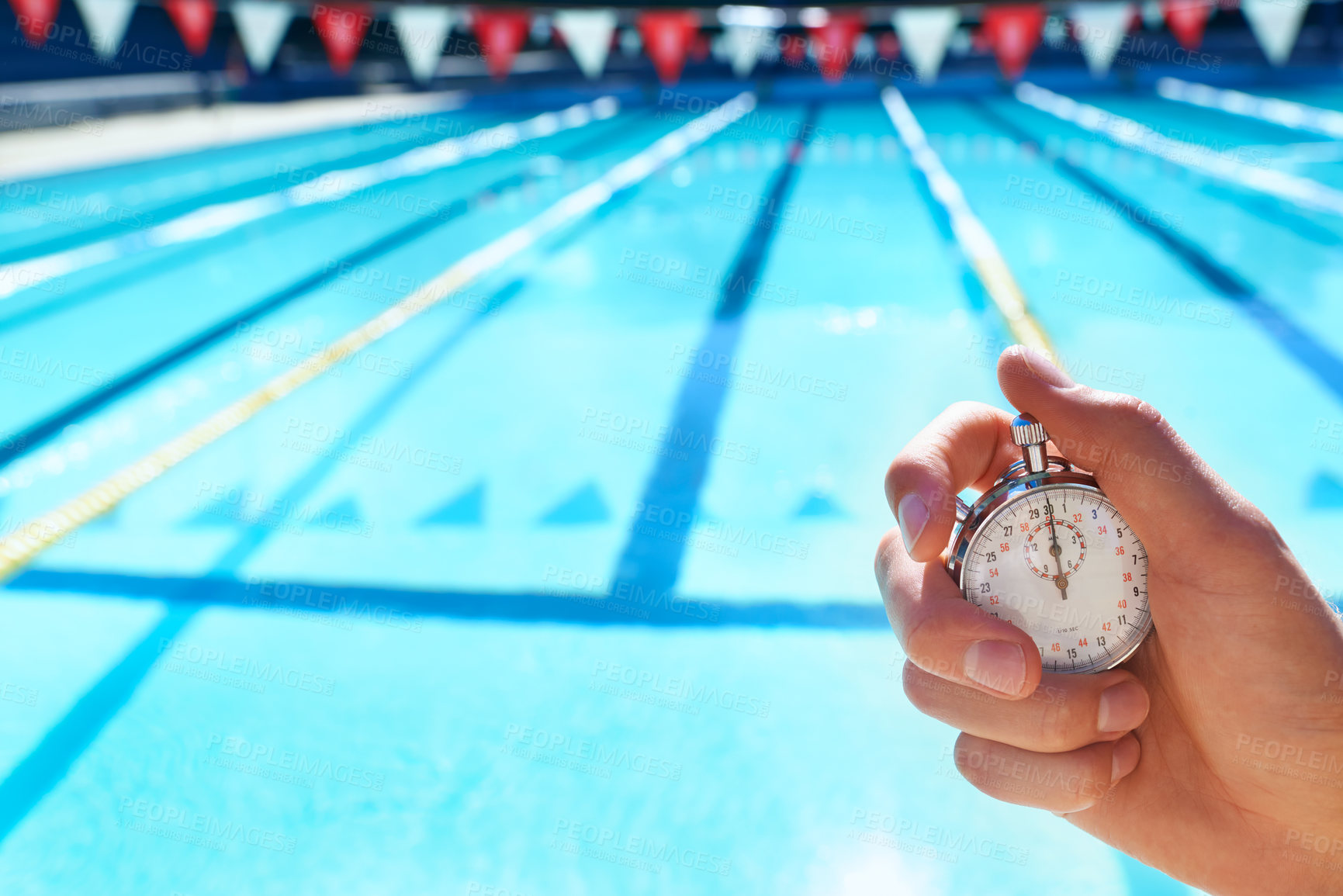 Buy stock photo Cropped shot a hand holding a stopwatch infront of a swimming pool