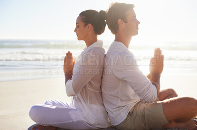 Buy stock photo A young couple performing a relaxing yoga routine together on the beach