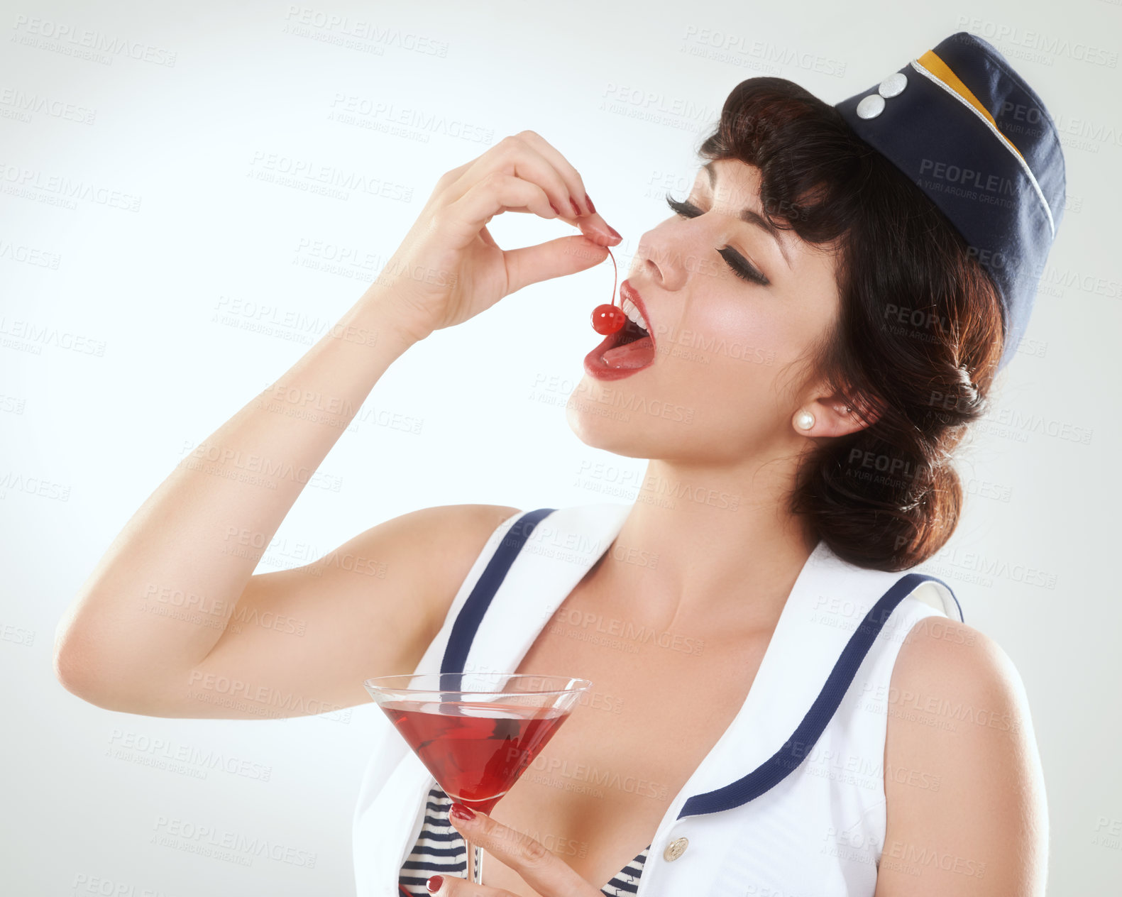 Buy stock photo Cocktail, stewardess and woman eating cherry in studio isolated on white background. Red martini, glass and air hostess enjoy alcohol fruit, vintage pin up girl or flight attendant travel on journey